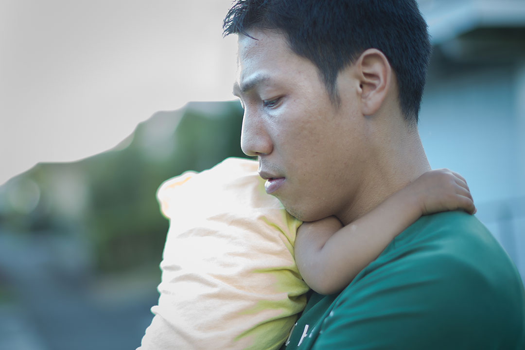 man looking down and holding a baby